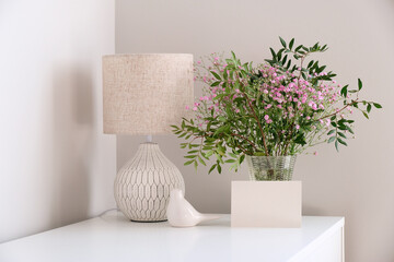 Cozy home desk table with lamp, bunch of spring flowers in vase, greeting card mockup. Hygge, boho...