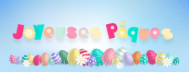 Texte «Joyeuses Pâques» aux couleurs pastels avec de jolies oeufs colorés et des fleurs alignés sur un fond bleu © Loks