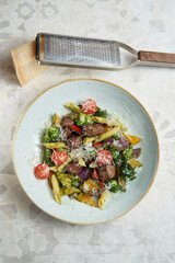 penne pasta with meat, parmesan cheese, tomatoes and pesto sauce