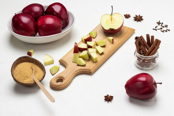 Chopped apples on cutting board. Brown sugar in coconut shell.