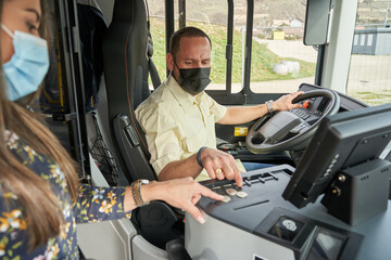 male driver selling a bus ticket to a female passenger