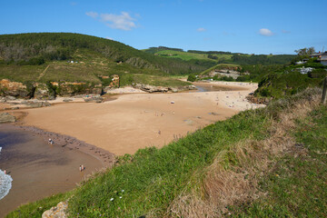 Cliffs surrounded by green vegetation under a blue sky.