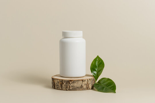 White mockup medical bottle of pills or vitamins on wooden stand with green leaf, organic medication, bio supplement