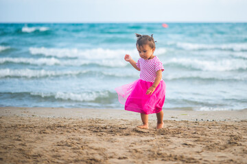 Portrait of cute little girl with pink dress on the beach.