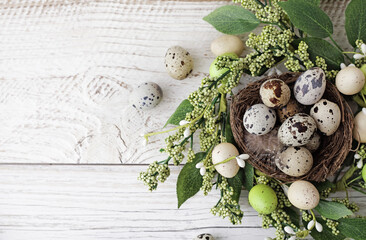 green wreath with easter quail eggs and flowers on wooden background