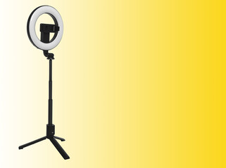 Selfie ring lamp with a tripod, on a white background and space for text on a yellow background
