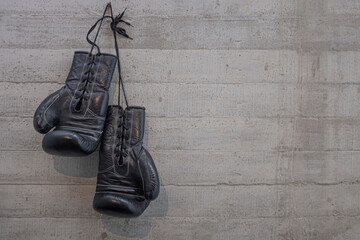 black boxing gloves hanging on a change room,  concrete wall