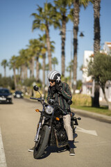 Closeup of a man with a motorcycle posing in stylish clothes © Victor Rangel/Wirestock Creators