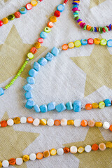 Top view of colorful handmade necklaces and bracelets made of beads, jewelry on the cloth background