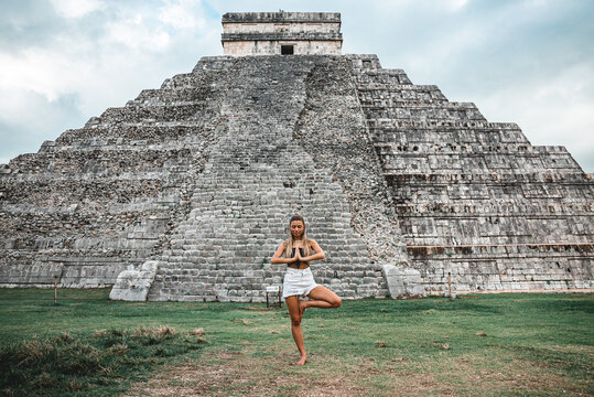Young caucasian female standing in a yoga position against the Chichen Itza