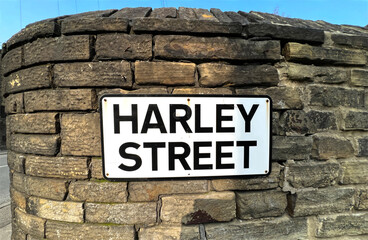 Harley Street road sign, affixed to an old stone wall, in the post industrial town of, Brighouse, UK