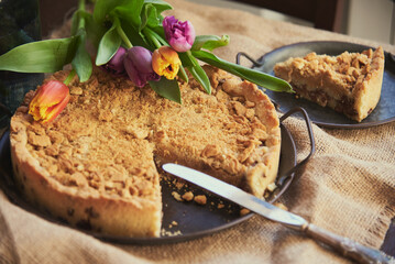 Homemade cake and a piece cut from it on vintage plates next to a bouquet of tulips.