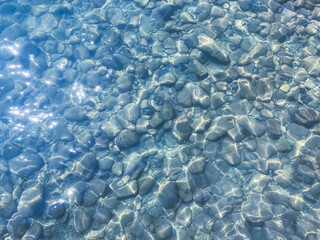 Shining Stone Pebbles Underwater. Under Ñlear Turquoise Water Through the Stream on the Pebbles with Seaweed