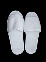 White disposable slippers on a black background.