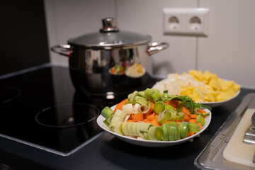 Closeup shot of boiling water in a pot and vegetables cut for salad