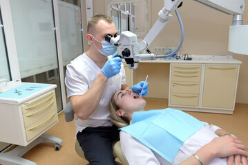 Fototapeta premium Doctor dentist treats the teeth of a patient under a microscope. Dentistry concept.