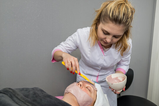  beautician applying alginate mask on face to woman salon