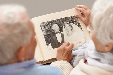Remembering like it was yesterday. Shot of a senior couple leafing through their wedding album.
