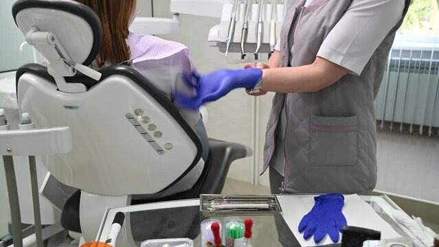 Dentist puts on gloves before examining a patient