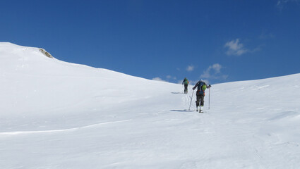 Fototapeta na wymiar Two man climbing up with tour ski. White landscape, blue sky. Fresh day. Slovenia, Julian Alps, Triglav national park, Komna 