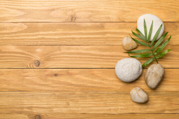 Fototapeta na wymiar Spa stones and leaves on wooden background, top view