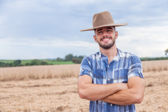 Portrait of young Latin farmer man in the casual shirt in the farm on the farm background.