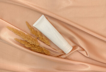 Cream mockup with embellishment on beige silk fabric. Gentle skin care concept.