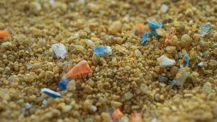Microplastics in the sand on the beach. Concept of global warming and climate change. Non-recyclable plastic pollution in the sand.