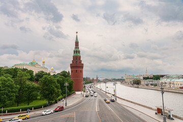 Embankment of the Moscow River with many cars. The towers of the Moscow Kremlin against the background of a cloudy spring sky