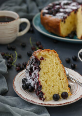Homemade curd pie with black currant with a cut piece of cake located on a dark background