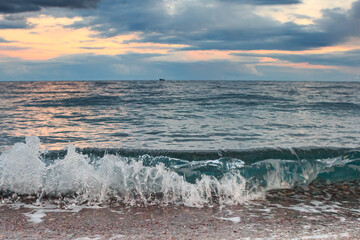 Rocky shore of the Mediterranean Sea against the background of orange clouds and ships Turkey, Antalya, Cirali.