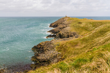 Grassy headland or peninsula with coastguard lookout in distance.