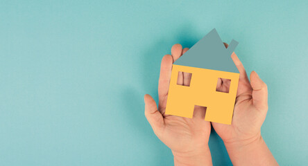 Holding a small paper house in the hands, planningto buy a new home, real estate, owning property
