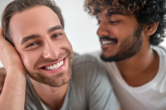 Curly-haired guy gazing at his handsome boyfriend