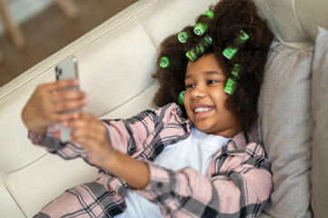 Girl lying on sofa taking selfie on smartphone