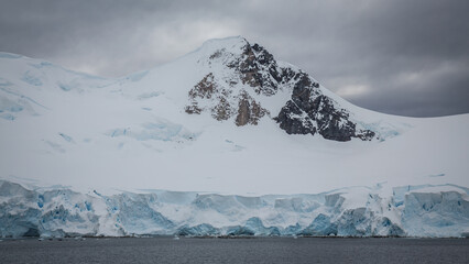 Die Spitze eines Granitberges ragt aus dem ewigen Eis der Antarktis, umringt von weiß blauen...