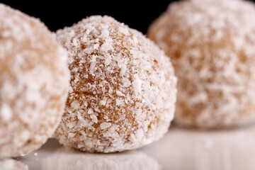 Beautiful sweets with coconut on a white plate on a black background