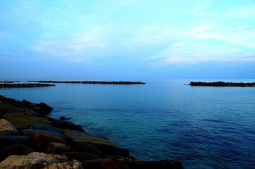 Deep blue Adriatic sea with a coast full of massive rocks under the azure evening sky in Pedaso