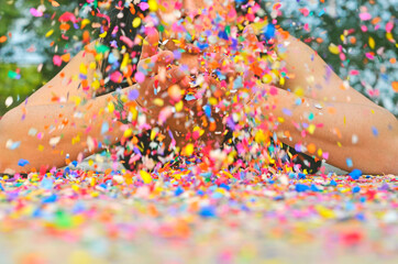 Mujer en el suelo soplando confeti multicolor