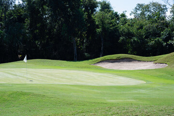 Panoramic view of a golf course with greens and sand bunkers surrounded by tropical plants in Mexico