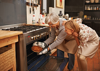 Getting baked. Shot of young woman learning baking tips from her grandmother.