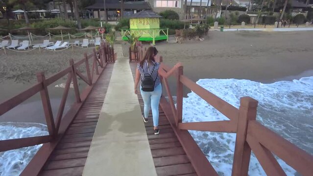 chica paseando por un puente rojo en la ciudad de marbella