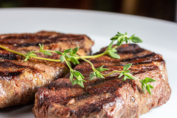Grilled marbled beef steak lies on a white plate