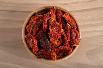 Bowl of dried tomatoes on wooden background, directly above	