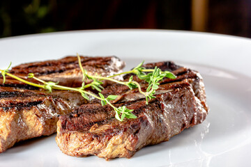 Grilled marbled beef steak lies on a white plate
