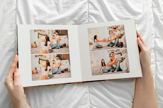 a hands holds a book with photos of mom, dad and daughter in the photo studio.