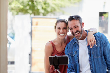 Naklejka premium Caption Newlyweds. Cropped shot of an affectionate couple taking a selfie together with a selfie stick outdoors.