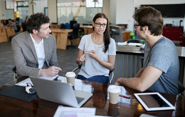 THe ideas are flowing. Shot of three coworkers talking together in an office.