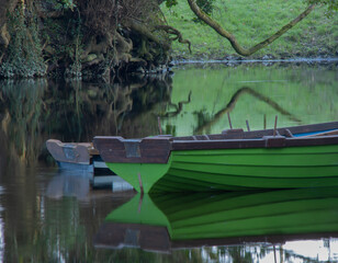Fototapeta na wymiar green boat on the river with green reflections
