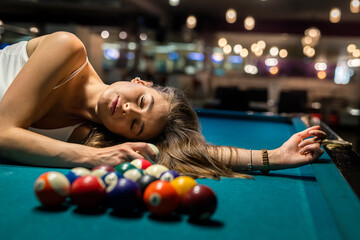 charming woman in a white T-shirt lies on a pool table